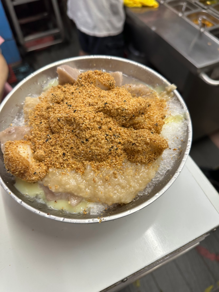 白胖軟Q的手工麻糬在鍋裡翻滾，熱麻糬裹上花生粉與芝麻粉，搭配煉乳刨冰，冰熱交織、香氣濃郁。