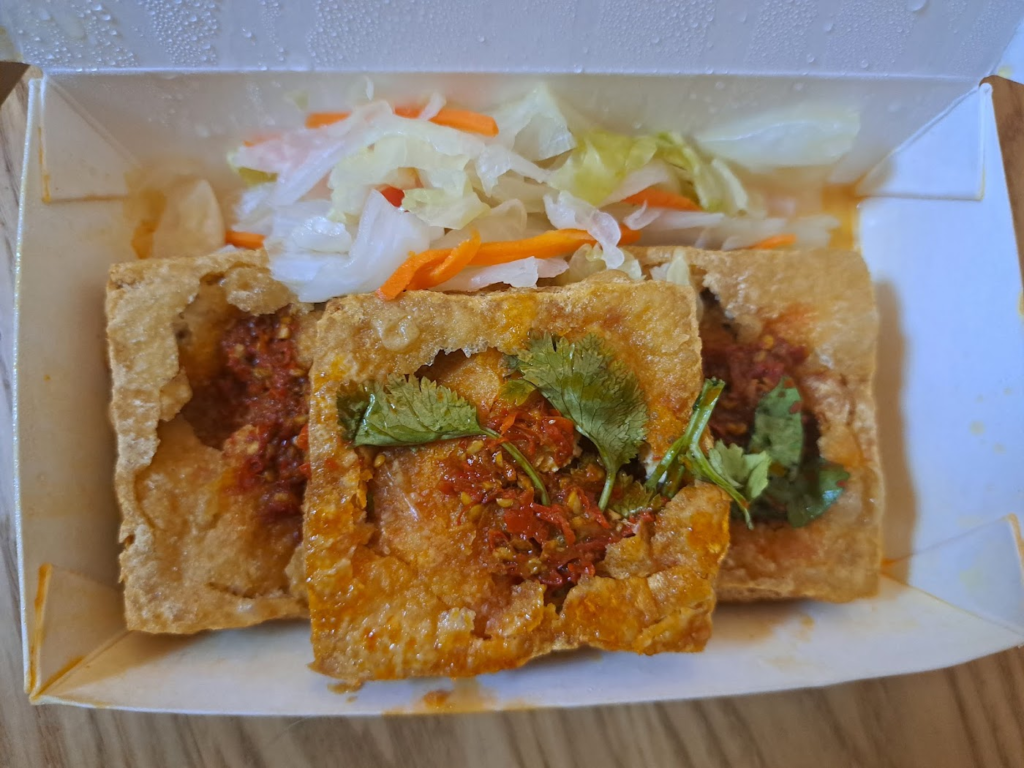 金黃酥脆的臭豆腐灌入蒜汁與醬料，搭配爽脆台式泡菜，旁邊是一碗熱騰騰麻辣腸旺臭豆腐鴨血，湯色紅亮香氣四溢。